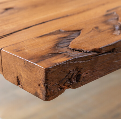 Detailansicht einer Altholz-Tischplatte mit rustikaler Kante, sichtbarer Maserung und Gebrauchsspuren.