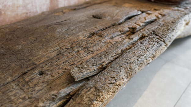 Detailaufnahme einer massiven Altholzplatte: rustikale Oberfläche mit Rissen und Patina, handwerklich verarbeitet in der Antikholzwerkstatt.