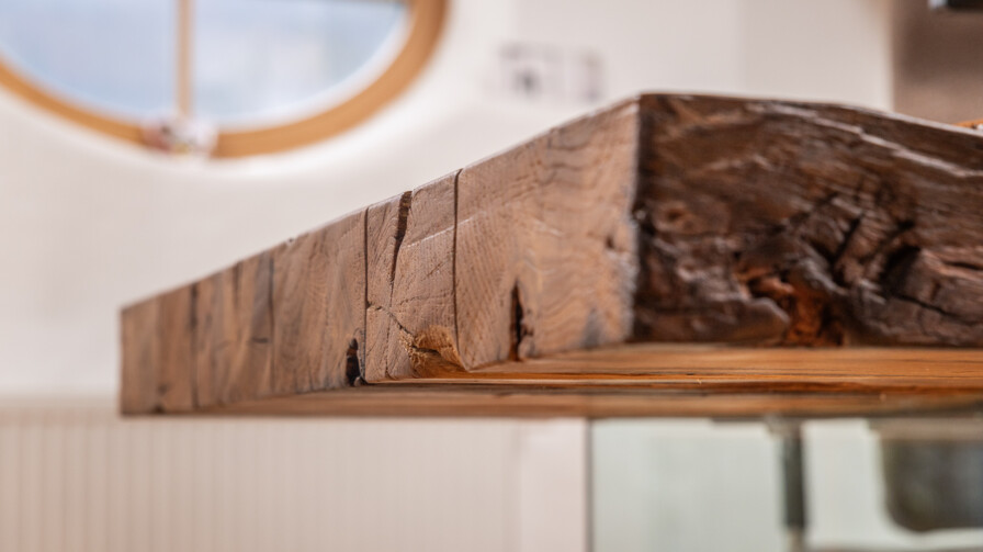 Nahaufnahme einer Altholzplatte mit sichtbarer Maserung und Rissen – handgefertigtes Möbel aus Altholz.