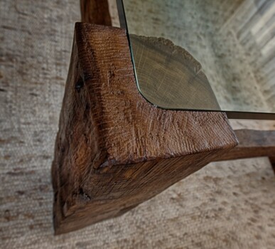 Detail eines handgefertigten Altholz-Tisches mit präzise eingelassener Glasplatte und rustikaler Oberfläche.