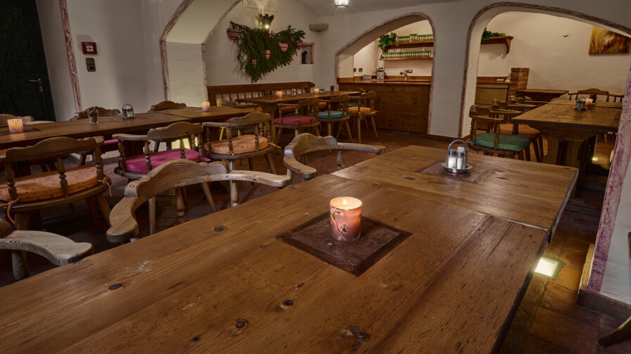 Gemütlicher Gastraum mit Altholz-Tischen, Kerzenlicht und Gewölbe.