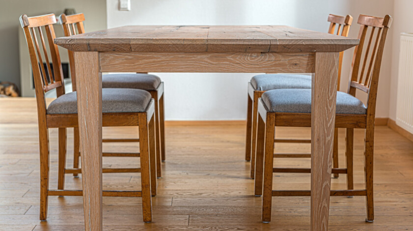 Esstisch mit vier gepolsterten Stühlen, gefertigt als Möbel aus Altholz, steht in einem hellen Raum mit Holzboden.