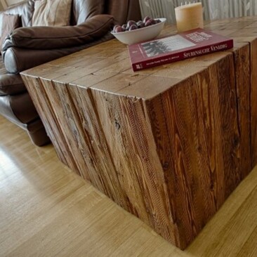 Blockförmiger Couchtisch aus Altholz im Wohnzimmer, mit Schale, Buch und Kerze.