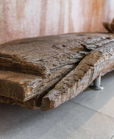 Massive Bank aus Altholz mit naturbelassener Kante auf Metallfüßen.