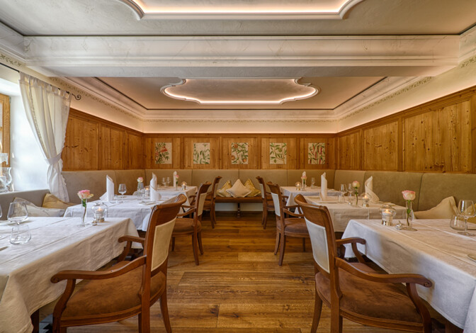 Stilvoller Gastraum mit Holzvertäfelung, weißen Tischtüchern und warmem Licht.