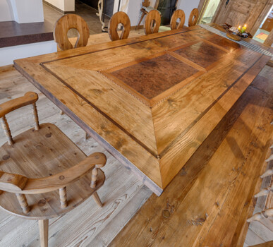 Rustikaler Esstisch mit Bank und Stühlen, als Möbel aus Altholz handgefertigt, in einer gemütlichen Stube.