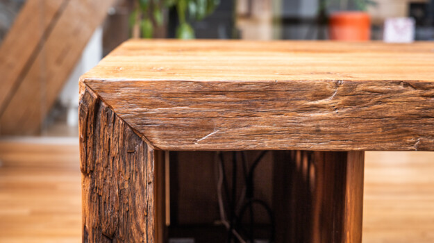 Nahaufnahme einer massiven Tischkante aus Altholz.