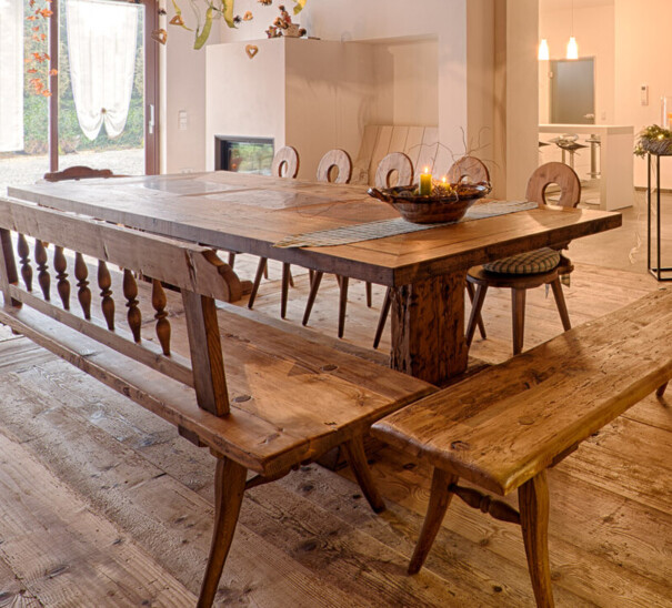 Rustikaler Essbereich mit langem Esstisch, Bank und sichtbaren Deckenbalken.