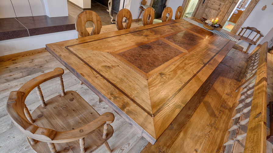 Rustikaler Esstisch mit Bank und Stühlen, als Möbel aus Altholz handgefertigt, in einer gemütlichen Stube.