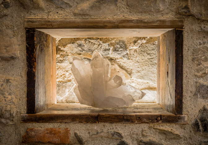 Bergkristall in beleuchteter Steinnische, eingerahmt von Altholz.