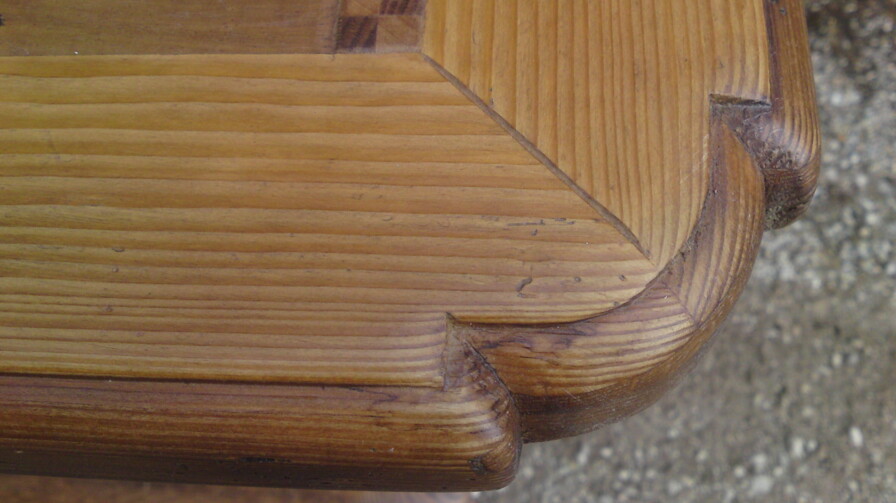 Detail einer abgerundeten Tischkante mit präziser Holzverbindung und Patina; restauriertes Möbel aus Altholz.