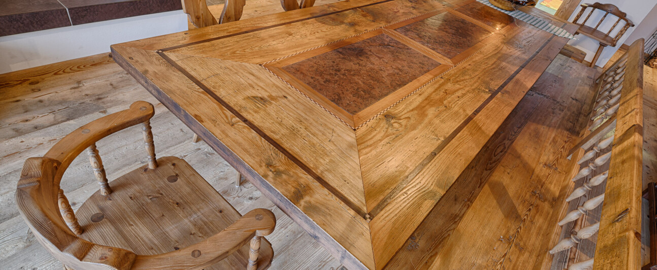 Rustikaler Esstisch mit Bank und Stühlen, als Möbel aus Altholz handgefertigt, in einer gemütlichen Stube.