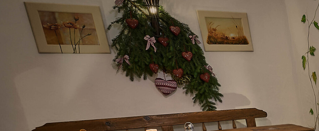 Gemütliche Gaststube mit großen Tischen und Bänken aus Altholz, Kerzenlicht und Deko.